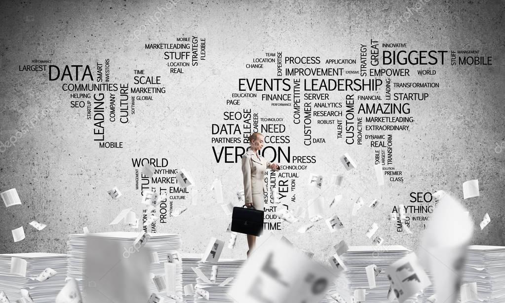 Business woman in suit standing among flying documents with business-related terms in form of world map on background. Mixed media.