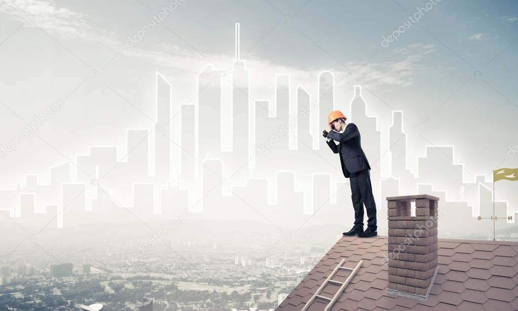 Young businessman in suit and helmet on roof 