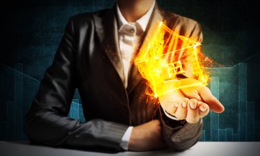 İşadamı yanan ev sembolü koyu arka plan duvara elleriyle tutmak siyah elbiseli closeup.