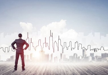 İşadamı arkasını dönüp modern iş merkezinin siluetine bakıyor.