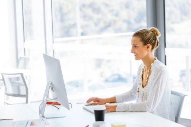 Masada oturan ve bilgisayarda çalışarak çekici genç kadın