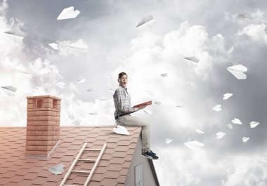 El ve gökyüzünde sosyal bağlantı kavramı kırmızı kitap ile ev üzerinde oturan genç öğrenci adam