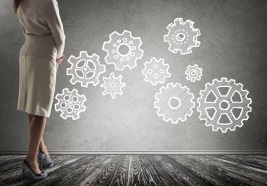 Duvarın önünde çekilmiş vites mekanizması, ekip çalışması kavramı ile ayakta işkadını alttan görünüm 