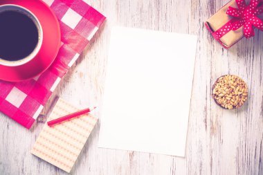 Tarif defteri kahve fincanı ve kurabiyeler ahşap masanın üstünde.