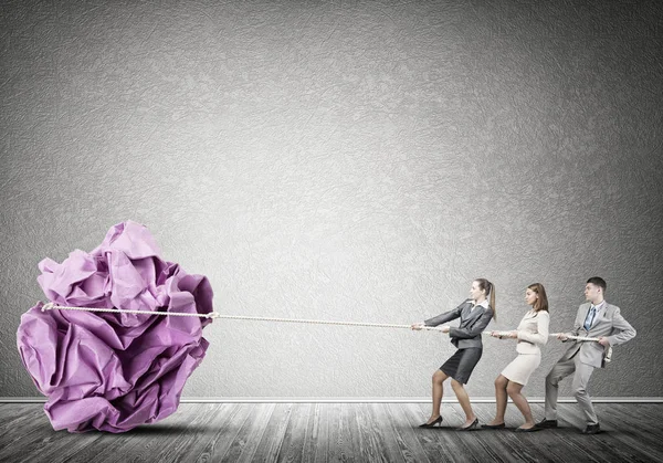 employees pulling together paper ball