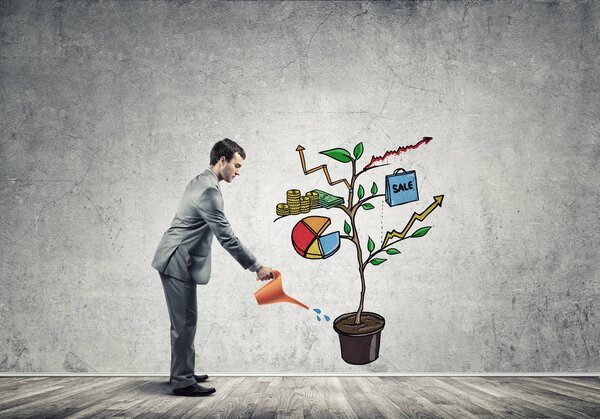 Handsome businessman watering drawn growth concept with can 