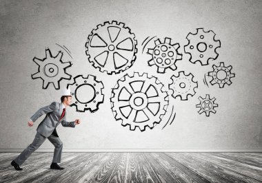 Beyaz kağıt kaplama giyen genç ve yakışıklı işadamı koşuyor ve duvarda dişli mekanizması var.