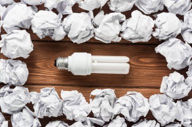 Akkor ampul ve buruşuk beyaz kağıt topları kahverengi ahşap tablo