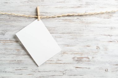 Tahta clothespins ile ip üzerinde asılı beyaz kağıt boş levha. Boyalı arka plan üzerinde zarif fotoğraf çerçeveleri. Scrapbooking ve el yapımı yaratıcılık. Metin için copyspace ile ahşap duvar