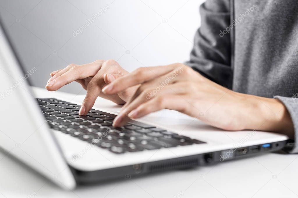 Student sitting at desk and working at laptop computer. Close-up of female hand typing at notebook computer. Journalist writing at workplace in office. Business innovation and digital technologies