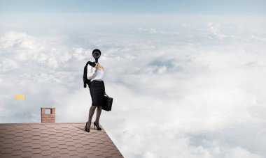 Evin çatısında baş durmak yerine kamerayla zum yapan yüzsüz iş kadını.