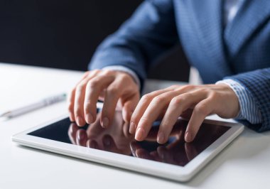 Dijital tablet dokunmatik ekranda yazarak erkek ellerin yakın çekim. İş elbisesi giyen adam masada oturuyor ve tablet bilgisayarda çalışıyor. Ofiste ki işyerinde yönetici. İş ve dijital teknoloji