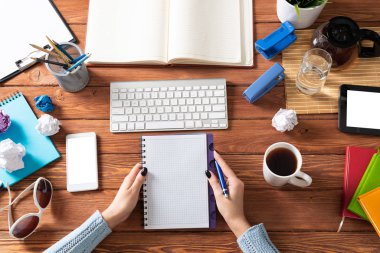 Ofis masasında defterini tutan iş kadını. İş muhasebesi ve danışmanlık. Kadın eli, dizüstü bilgisayarı ve belgeleri olan düz ofis işyeri. Dijital teknoloji ve modern çalışma alanı