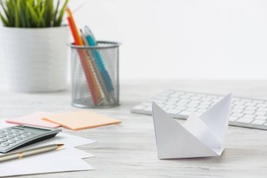 Beyaz origami teknesi olan ahşap ofis masası. Profesyonel yatırım stratejisi ve yönü. Çömlekte yeşil bitki, bilgisayar klavyesi ve hesap makinesi olan düz bir ofis. Kişisel fırsatlar