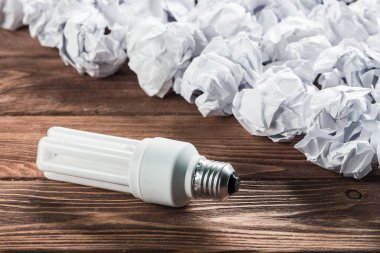 Akkor ampul ve buruşuk beyaz kağıt topları kahverengi ahşap tablo