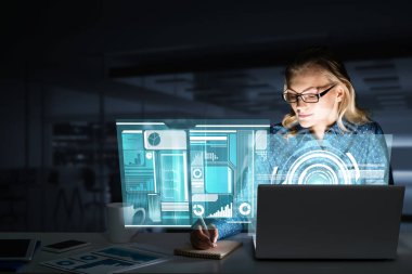 Çekici bir kadın gece ofisinde oturmuş dizüstü bilgisayarına bakıyor. Karışık ortam