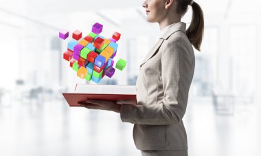 Açık kitabın üzerinde renkli geometrik 3d küp kompozisyonu gösteren bir kadın. Dijital teknoloji ve yenilik çözümleri kavramı. Bulanık ışık arkaplanı üzerine açık kitabı olan iş kadını.