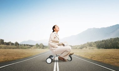 Beyaz kadın asfalt yolda çocuk bisikleti sürüyor. Beyaz takım elbiseli genç bir işçi dışarıda bisiklet sürüyor. Beceriksiz ve yetersiz iş metaforu. Bisikletçi ile başlangıç seviyesi konsepti.