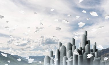 Açık havada, arka planda güzel manzarası olan uçan kağıt uçaklar arasında yer alan yüksek ve büyük taş sütunların resmi. Duvar kağıdı, telif alanı olan arkaplan.