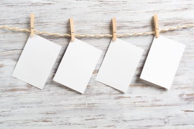 Tahta arka planda ip üzerinde asılı boş kağıt levhalar. Copyspace ile Vintage romantik kompozisyon. Aile fotoğraf çerçeveleri. Tahta çamaşır iğneli ip. Scrapbooking ve el yapımı yaratıcılık
