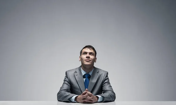 Smiling man folded hands and looking upward. — Stock Photo, Image