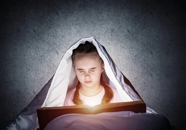 Przestraszony dzieciak z otwartą książką i latarką — Zdjęcie stockowe