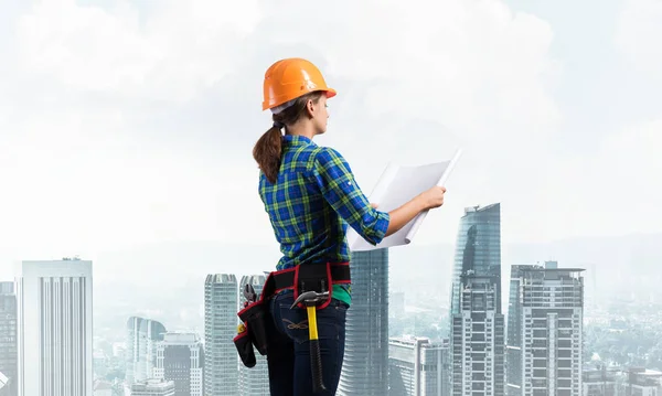 技術的な青写真とハードハットの女性エンジニア 市街地を背景に建設を検査チェックブルーシャツで女性建築家の側面図 プロジェクト管理の構築 — ストック写真
