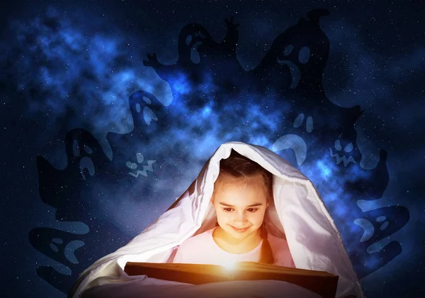就寝後にベッドで本を読む熱狂的な小さな女の子 パジャマ姿の子供 懐中電灯が毛布の下に隠れている 深い青の背景に恐ろしい女の子と想像上のモンスター おとぎ話を読む子供 — ストック写真