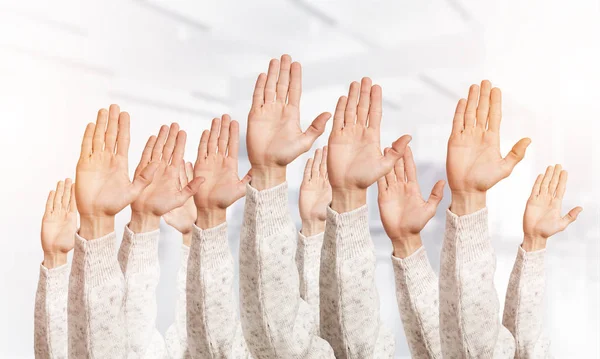 Row of man hands showing voting gesture. Participation and agreement group of signs. Human hands gesturing on light blurred background. Many arms raised together and present popular gesture.