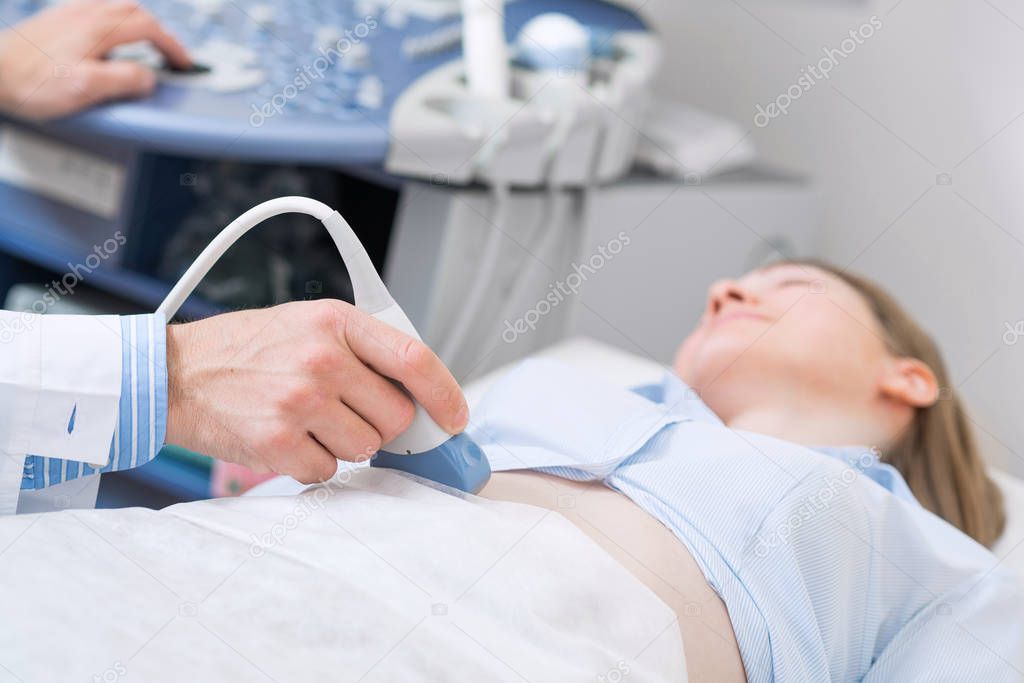 Sonographer using ultrasound machine at work. Modern clinical diagnostics and treatment. Close-up ultrasound scanner in hand of doctor. Doctor ultrasound examine female patient abdomen at hospital.