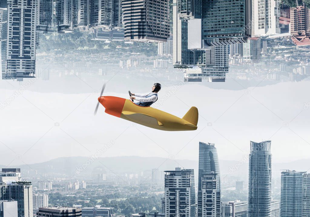 Businessman flying in small airplane. Two modern urban worlds located upside down to each other. Funny man in aviator hat and goggles driving propeller plane. Business center with skyscrapers