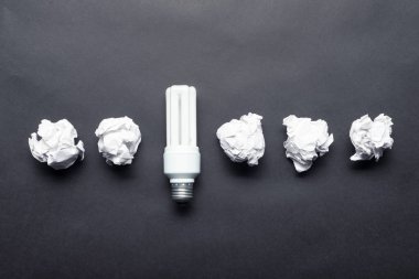 Floresan lamba ve siyah arka plan üzerinde buruşuk beyaz kağıt topları. Fikir üretimi ve beyin fırtınası motivasyonu. Başarılı ve başarısız fikirlerin iş kavramı. Yaratıcı ve dahice çözümler