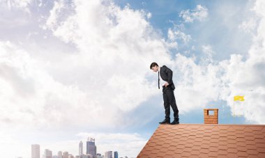 Genç işadamı tuğladan çatının kenarında dikilip aşağıya bakıyor. Karışık ortam