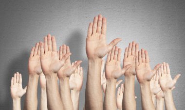 Oy verme jestini gösteren bir sıra adam eli. Katılım ve anlaşma işaretleri grubu. İnsan elleri gri duvarın arka planında siler. Birçok kol birlikte kaldırdı ve mevcut popüler jest.