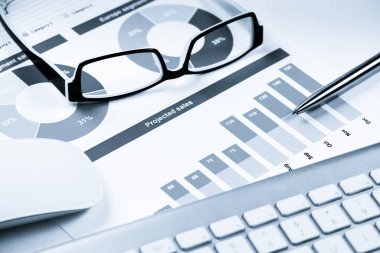 Klavye gözlüklü ve mali belgeleri masada olan iş yeri