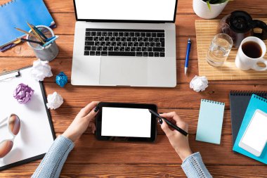 Ofis masasında çalışan bir iş kadını. Düz tahta masa, dizüstü bilgisayarı ve beyaz ekranlı tablet bilgisayarı vardı. Kadın eli ile üst düzey ofis işyeri. Çevrimiçi iş ve internet ticareti