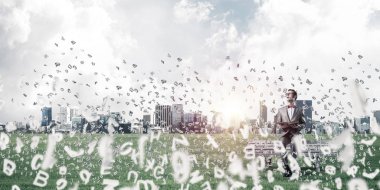 Kırmızı gözlüklü ve takım elbiseli komik adam bankta oturup kitap okuyor.