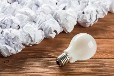 Akkor ampul ve buruşuk beyaz kağıt topları kahverengi ahşap tablo