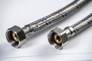 İç vida bağlayan su örgülü metal hortum. Esnek hidrolik sistemi kapatın. Sıhhi tesisat boru hattı masaya yatıyor. Banyo tamiri veya inşaat hizmeti için yeni ekipmanlar.