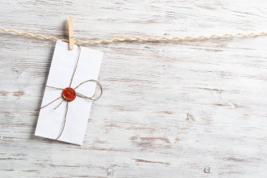 Beyaz zarf ahşap arka planda ipte sallanıyor. Ahşap mandallı ip. Üzerinde balmumu mühür damgası olan bir zarf. Retro iletişim ve yazışmalar. Teslimat servisi düzeni