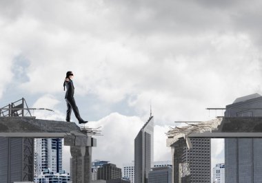 Gizli tehditlerin ve risklerin sembolü olarak beton köprüde gözü kapalı yürüyen bir iş adamı. Arka planda şehir manzarası. 3B görüntüleme.