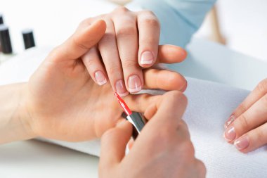 Güzellik salonundaki kadın manikür yaptırıyor. Profesyonel tırnak sanatları reklamı. Güzeller güzeli ve bakımlı bir kadın eli güzellik merkezine kırmızı oje sürüyor..