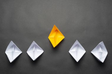 Siyah arka plan üzerinde kağıt gemi sırası. Yaratıcı yenilik ve liderlik iş kavramı. Düz yatıyordu sarı origami lider tekne önde diğerleri tekneler. Kopyalama alanı ile sosyal pazarlama düzeni.