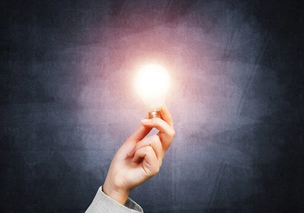 人的手与发光白炽灯在背景墙上 发电符号 电灯泡成功的解决方案概念 领导能力和商业动机 — 图库照片