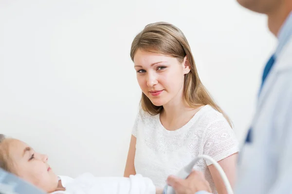 家庭保健概念与母亲和女儿在诊所 用超声波设备对小女孩进行体格检查 儿童腹部的声像仪移动传感器 专业临床诊断 — 图库照片