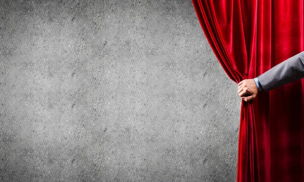 Concrete wall behind drapery curtain and hand opening it — Stock Photo, Image