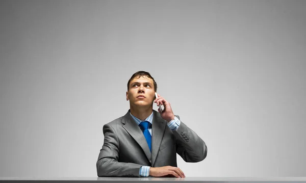 Young Man Talking Phone Looking Upward Businessman Sitting Desk Grey — Stock Photo, Image