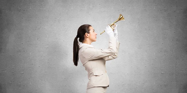 トランペットを吹く実業家 白いビジネススーツの若い女性と手袋は灰色の壁の背景に楽器でポーズ 音楽家とのビジネス支援とサポートの概念 — ストック写真