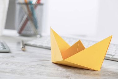 Ofis masası ve sarı kağıt gemisiyle iş adamı çalışma alanı. Pazarlama ve reklam. Bilgisayar klavyesi ve hesap makinesi olan düz tahta bir masa. Yaratıcı proje yönetimi ve liderlik