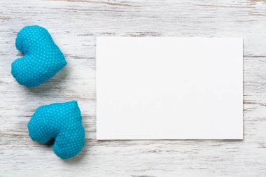 Boş kağıt ve el levha ahşap yüzey üzerinde yatan mavi kalpler yaptı. Copyspace ile Vintage romantik kompozisyon. Sevgililer Günün kutlu olsun. Dokulu doğal ahşap arka plan üzerine beyaz kağıt.